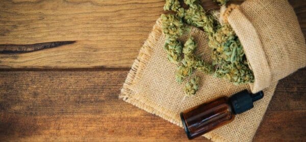 Wiet, wiet olie flesje, houten achtergrond.